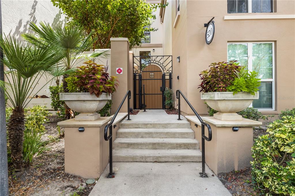 A concrete staircase with black metal railings leads to a gated entrance with large planters — 520 S ARMENIA AVENUE UNIT 1229E, TAMPA, FL