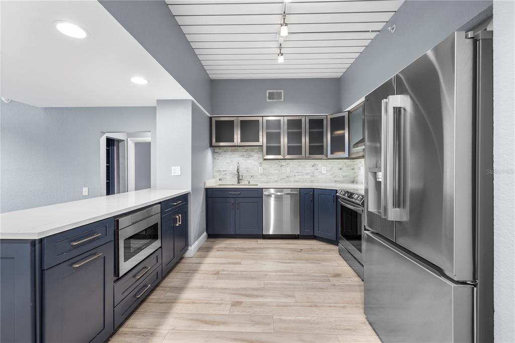 A kitchen features blue cabinets, stainless steel appliances, white countertops, and light wood-look flooring — 520 S ARMENIA AVENUE UNIT 1229E, TAMPA, FL