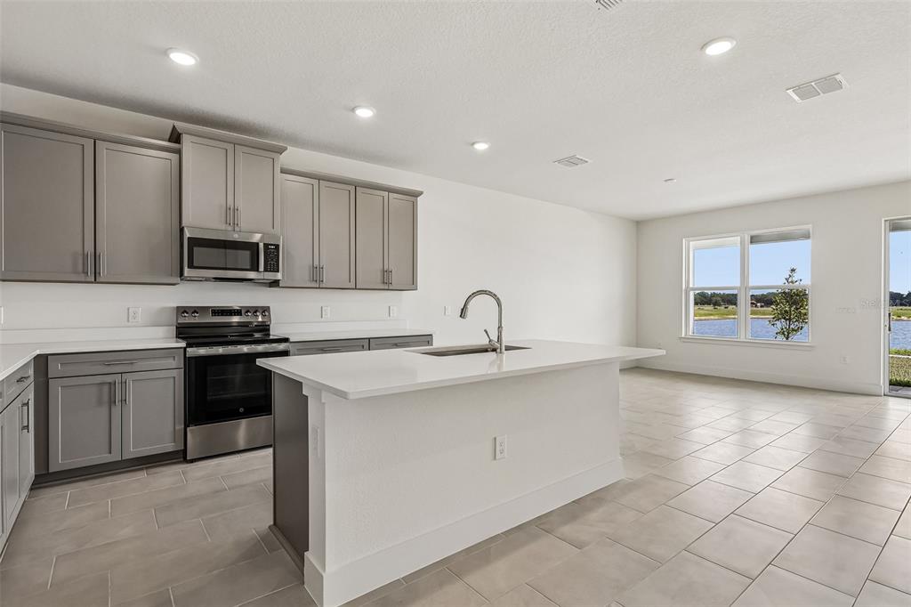 A kitchen with gray cabinets, white countertops, a center island, and a view of water — 5030 SALADO DRIVE, ST CLOUD, FL