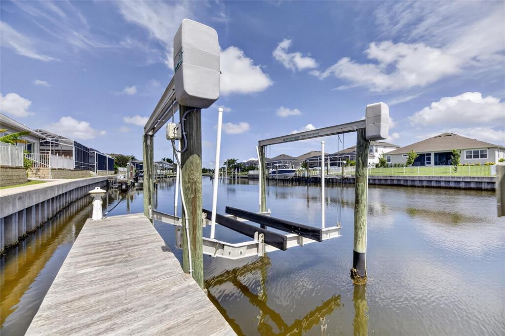 A wooden dock features a boat lift over a canal in a residential neighborhood — 715 ISLEBAY DRIVE, APOLLO BEACH, FL