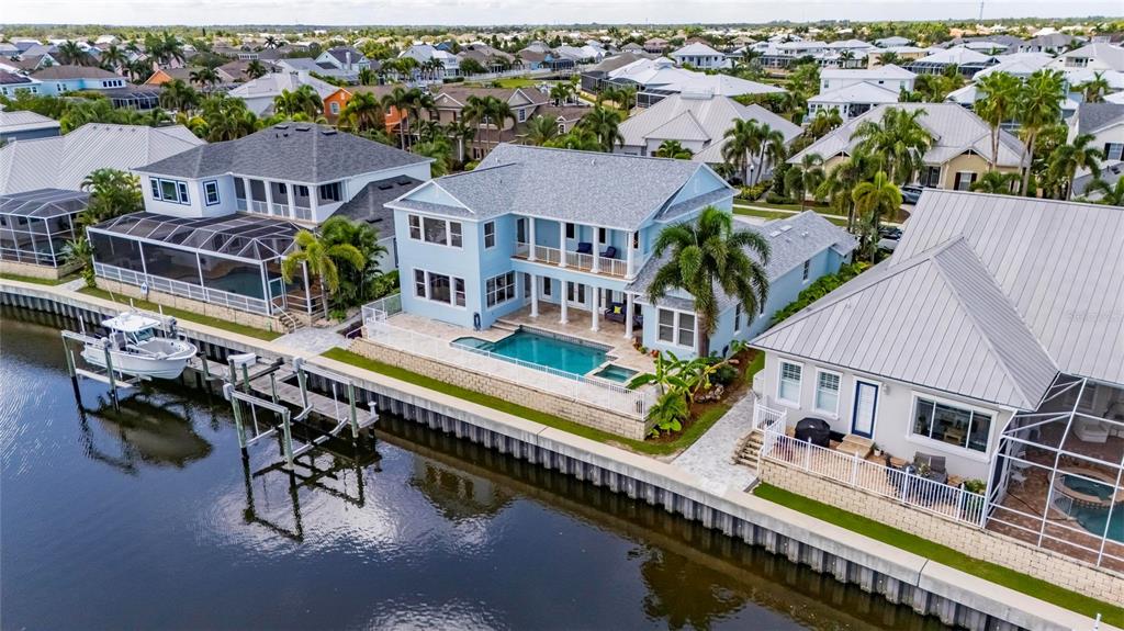 An aerial view of a blue two-story waterfront house with a pool and private dock — 715 ISLEBAY DRIVE, APOLLO BEACH, FL