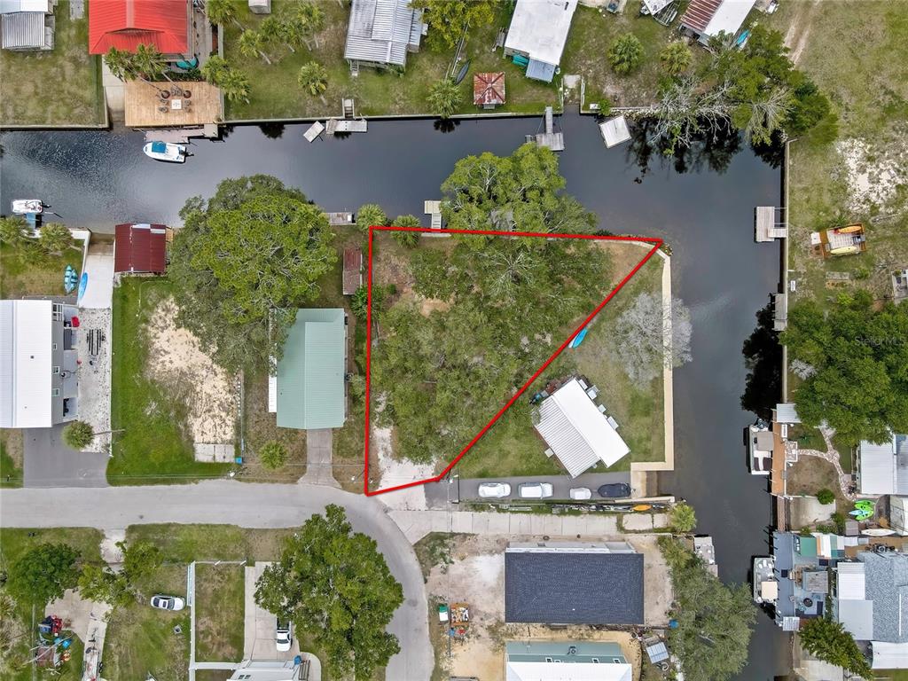 An aerial view shows a triangular waterfront lot outlined in red along a canal — 6134 ISLAND DRIVE, WEEKI WACHEE, FL