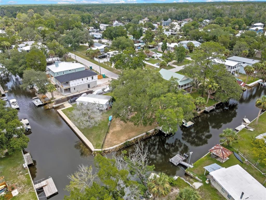 An aerial view shows a waterfront property with a canal, boat docks, and surrounding houses — 6134 ISLAND DRIVE, WEEKI WACHEE, FL