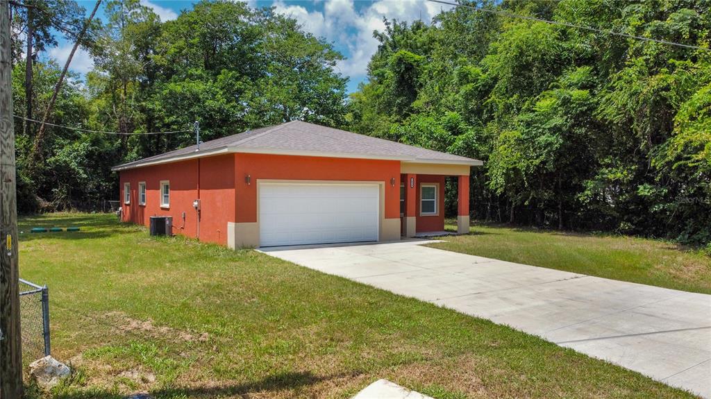 A single-story orange house with a white garage door and a concrete driveway — 5030 SW 63RD COURT, GAINESVILLE, FL