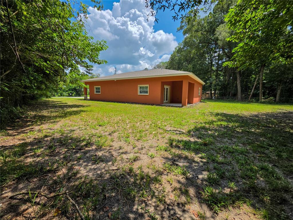 The exterior of a single-story orange house sits on a grassy lot with trees — 5030 SW 63RD COURT, GAINESVILLE, FL