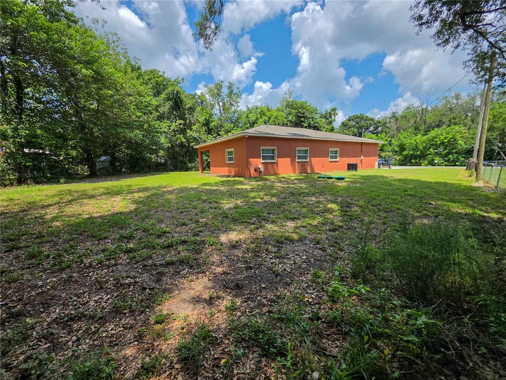 A single-story orange house with a hip roof sits on a large, grassy lot — 5030 SW 63RD COURT, GAINESVILLE, FL