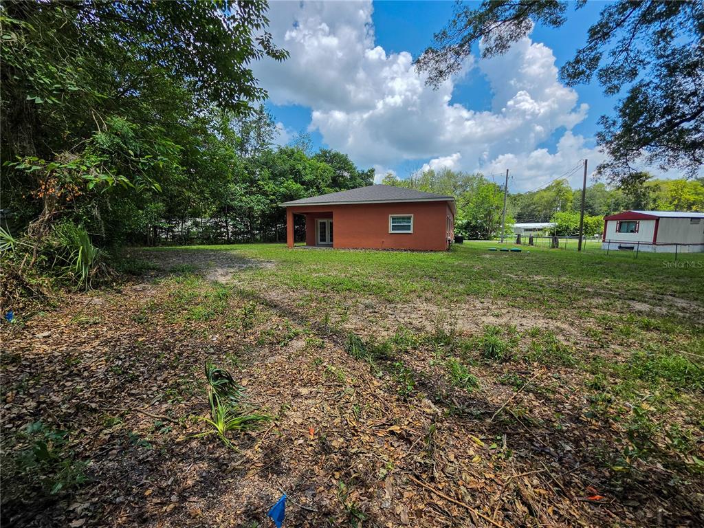 A view of the exterior of a small orange house with a large yard — 5030 SW 63RD COURT, GAINESVILLE, FL