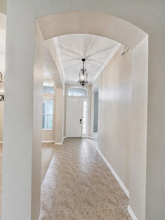 A tiled entryway features an arched opening, a hanging light fixture, and a white front door — 105 E BLUE WATER EDGE DRIVE, EUSTIS, FL