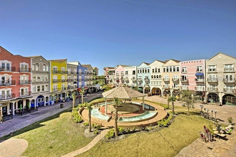 An aerial view shows a town square with a central fountain surrounded by colorful buildings — 101 PALM HARBOR PARKWAY UNIT A-308B, PALM COAST, FL