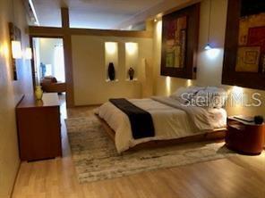 A bedroom features a bed with a dark runner, recessed wall niches, and wood flooring — 101 PALM HARBOR PARKWAY UNIT A-308B, PALM COAST, FL