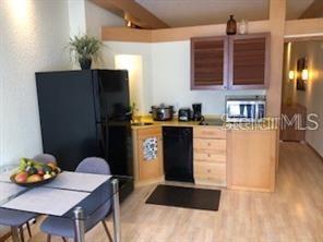 A kitchen features a black refrigerator, light wood cabinets, a dishwasher, and a small dining table — 101 PALM HARBOR PARKWAY UNIT A-308B, PALM COAST, FL