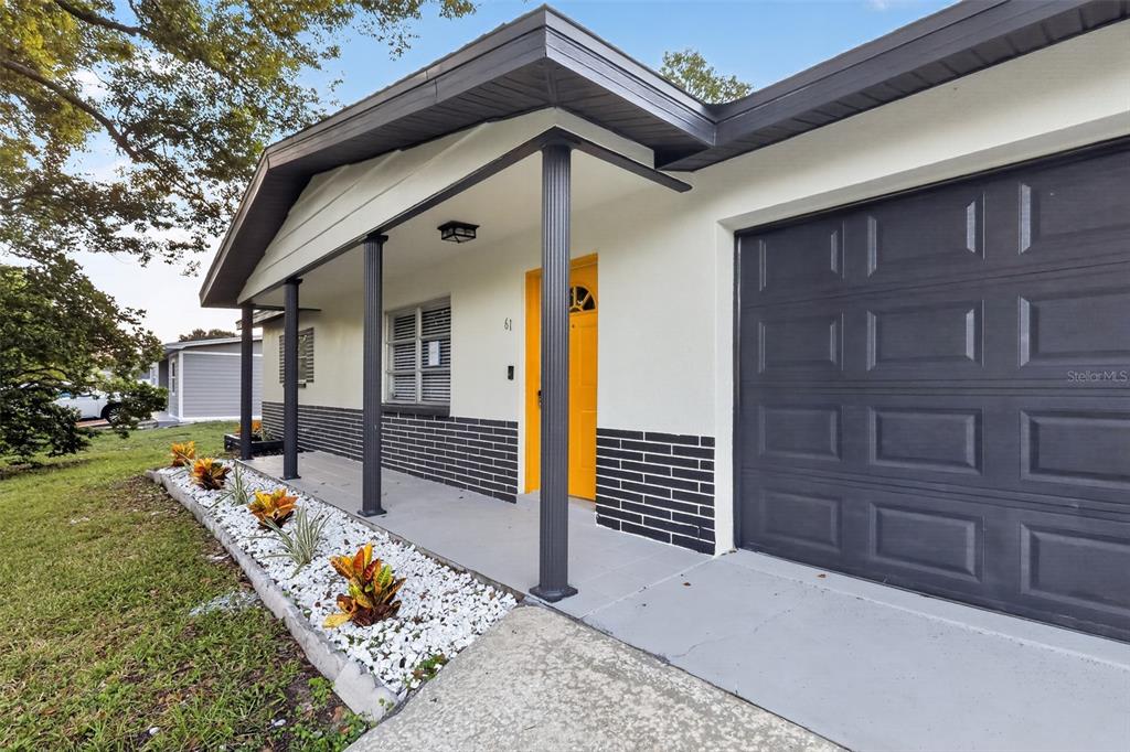 A single-story house exterior features a yellow front door, dark gray garage, and white landscaping — 61 S TYLER STREET, BEVERLY HILLS, FL