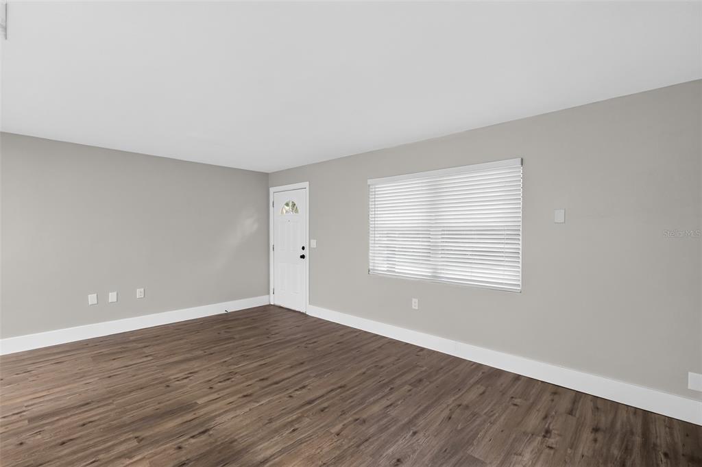 An empty room features gray walls, white trim, and wood-look flooring with a single window — 61 S TYLER STREET, BEVERLY HILLS, FL