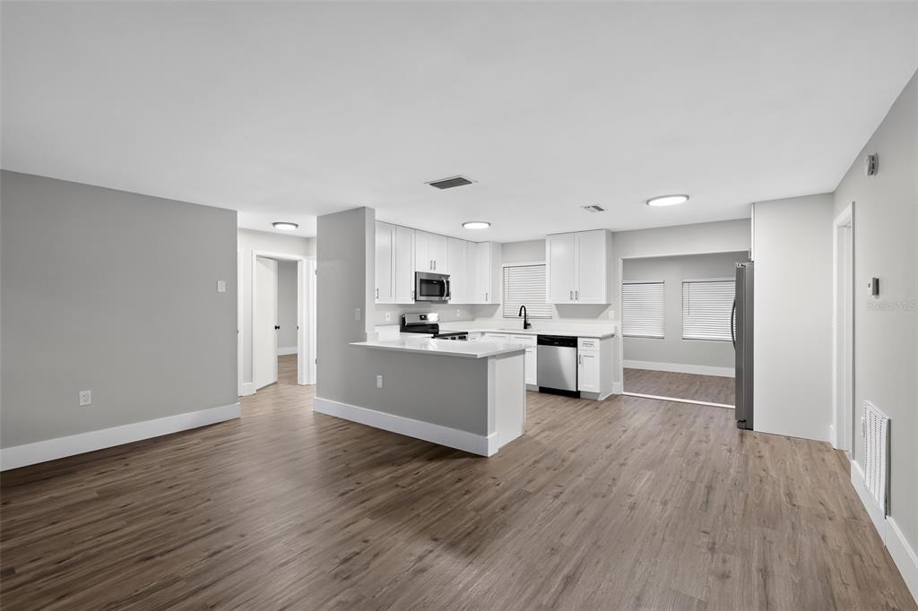 An open-concept kitchen features white cabinets, stainless steel appliances, and wood-look flooring — 61 S TYLER STREET, BEVERLY HILLS, FL