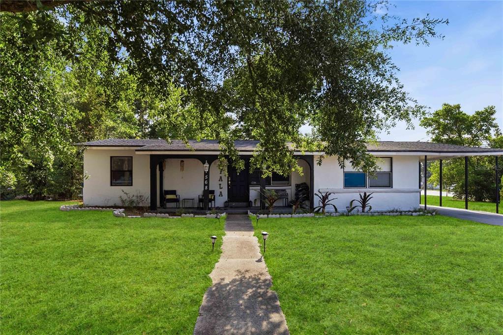 A single-story white house with a covered porch, a carport, and a concrete walkway — 568 E NORMANDY BOULEVARD, DELTONA, FL
