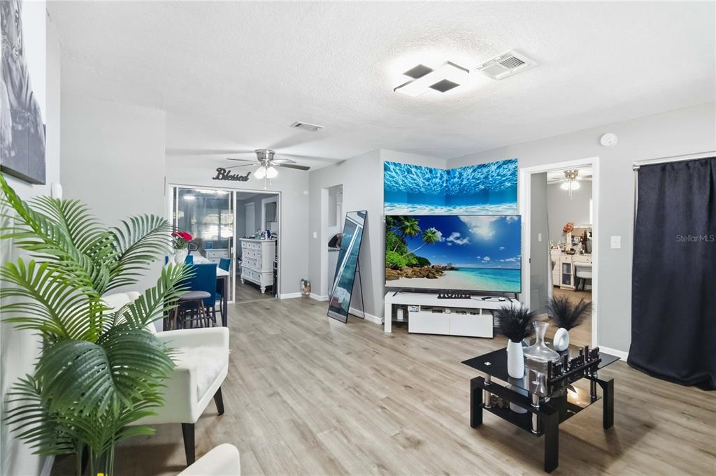 A living room features light wood flooring, a large television, and a white media console — 568 E NORMANDY BOULEVARD, DELTONA, FL