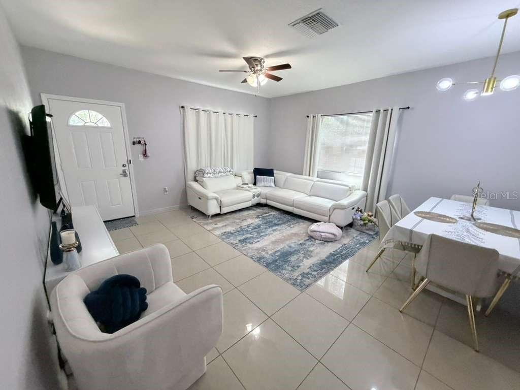 A living and dining area features white tile floors, a sectional sofa, and a dining table — 1818 SUNNY STREET, KISSIMMEE, FL
