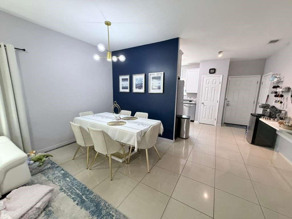 A dining area features a dark blue accent wall, a modern chandelier, and tiled flooring — 1818 SUNNY STREET, KISSIMMEE, FL