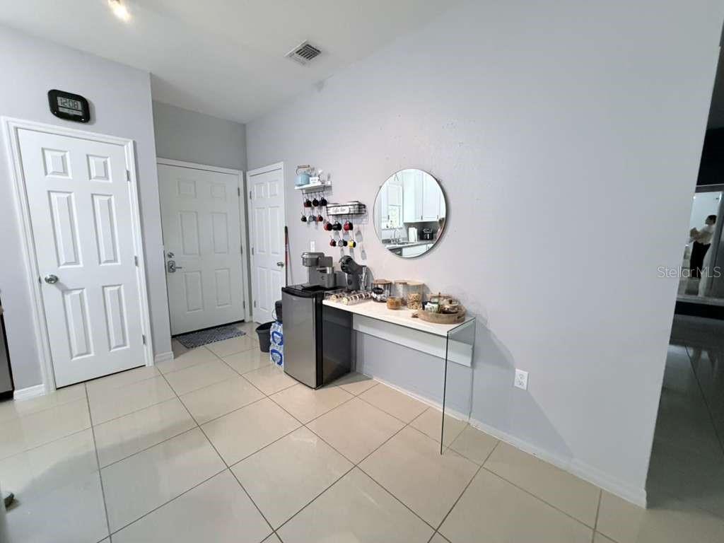 A room features light tile flooring, white doors, and a coffee station with a round mirror — 1818 SUNNY STREET, KISSIMMEE, FL