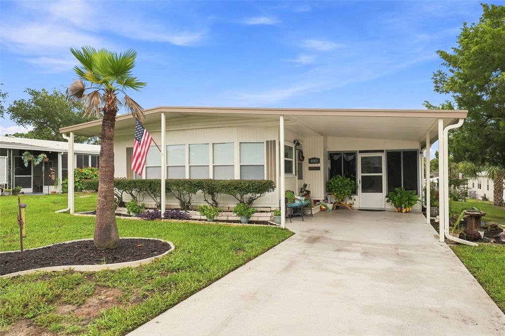 A single-story manufactured home features a concrete driveway, a carport, and a palm tree — 8082 DELLROSE AVENUE, BROOKSVILLE, FL
