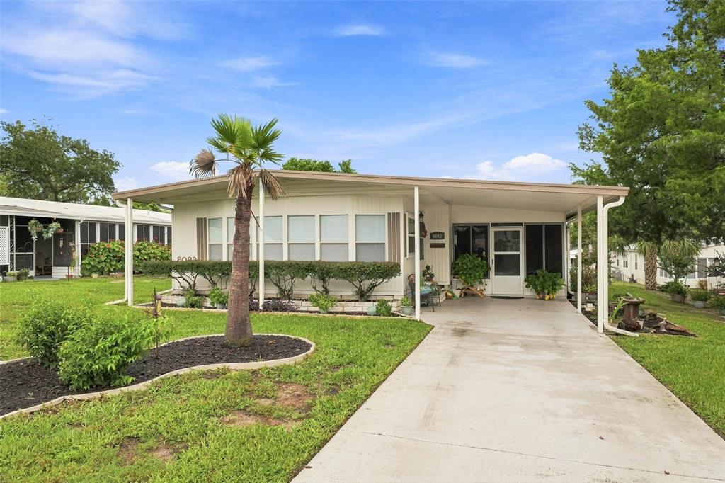 A single-story manufactured home with a carport, palm tree, and landscaped front yard — 8082 DELLROSE AVENUE, BROOKSVILLE, FL