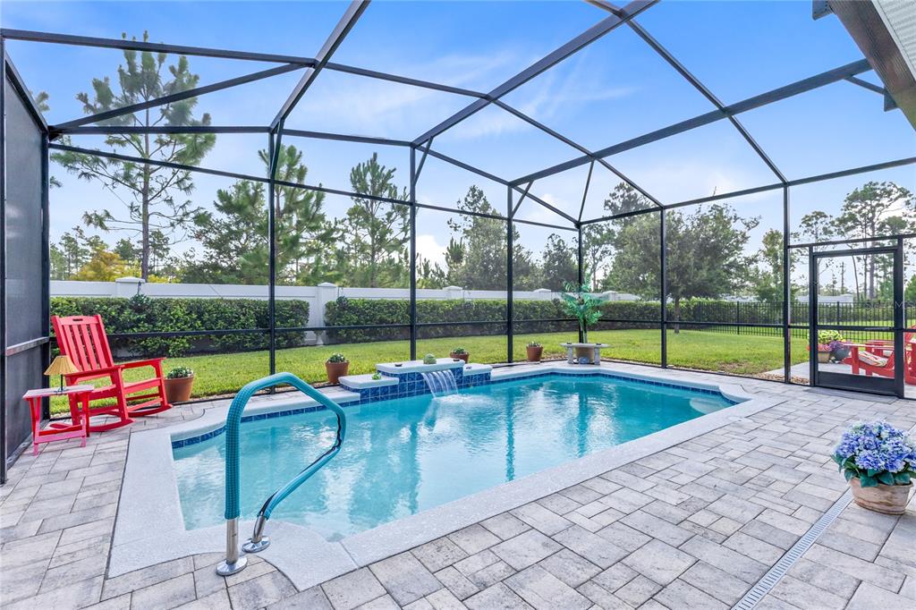 A screened-in patio features a rectangular swimming pool with a small waterfall and paver decking — 2865 CHERRY BLOSSOM LOOP, ST CLOUD, FL