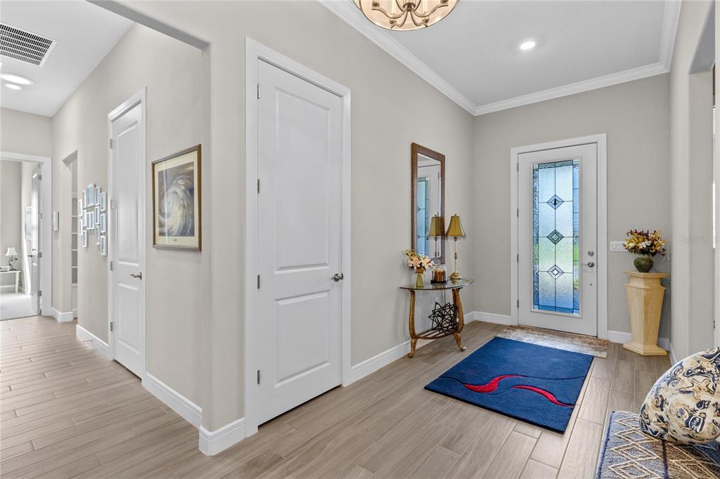 A bright entryway features light wood-look tile flooring, white doors, and a decorative front door — 2865 CHERRY BLOSSOM LOOP, ST CLOUD, FL
