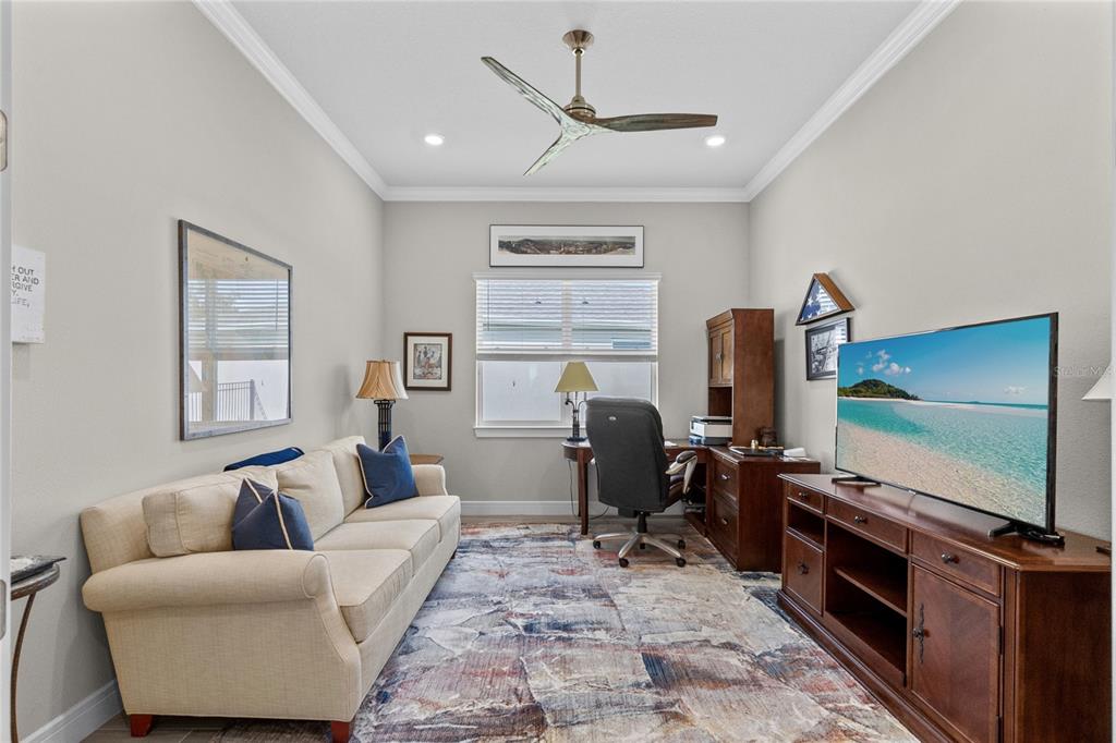 A home office features a beige sofa, a wooden desk with a chair, and a television — 2865 CHERRY BLOSSOM LOOP, ST CLOUD, FL