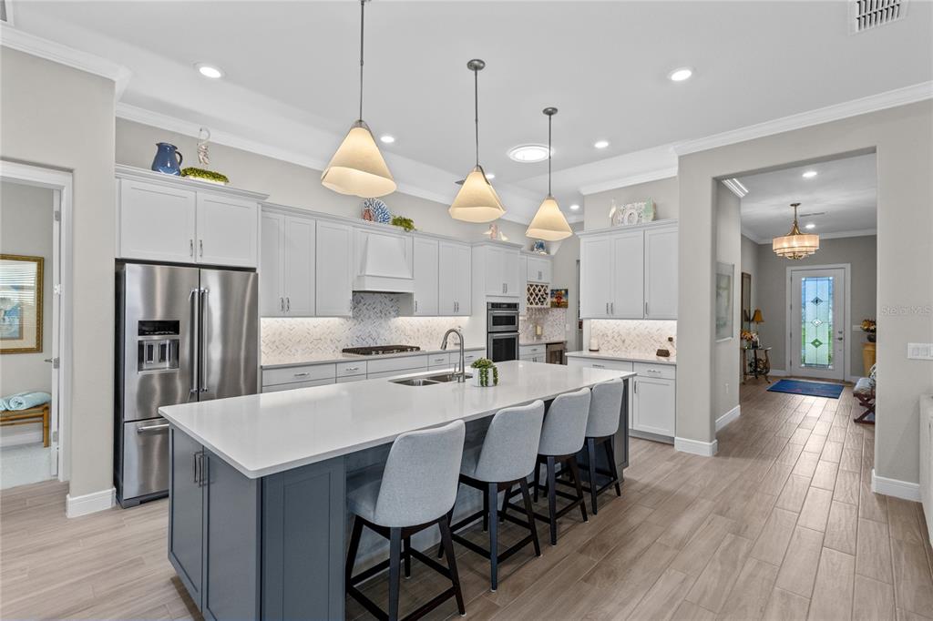 A modern kitchen features a large blue island, white cabinetry, stainless steel appliances, and tile flooring — 2865 CHERRY BLOSSOM LOOP, ST CLOUD, FL