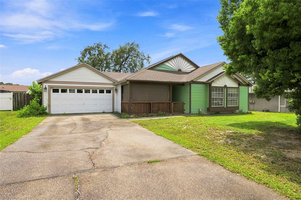 A single-story house with a green exterior, a front porch, and an attached two-car garage — 13094 LINDEN DRIVE, SPRING HILL, FL