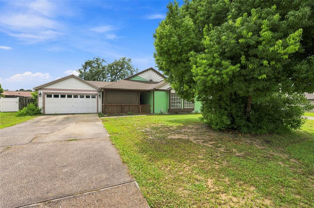 A single-story house with a white garage, green siding, and a large tree in front — 13094 LINDEN DRIVE, SPRING HILL, FL
