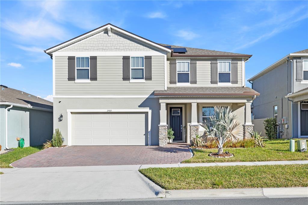 A two-story suburban house with a gray exterior, stone accents, and a two-car garage — 2985 AMBERSWEET PLACE, CLERMONT, FL