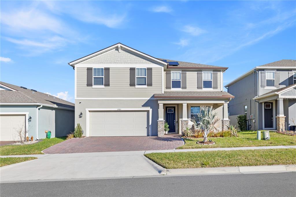 A two-story suburban house features a two-car garage, stone accents, and a paved driveway — 2985 AMBERSWEET PLACE, CLERMONT, FL