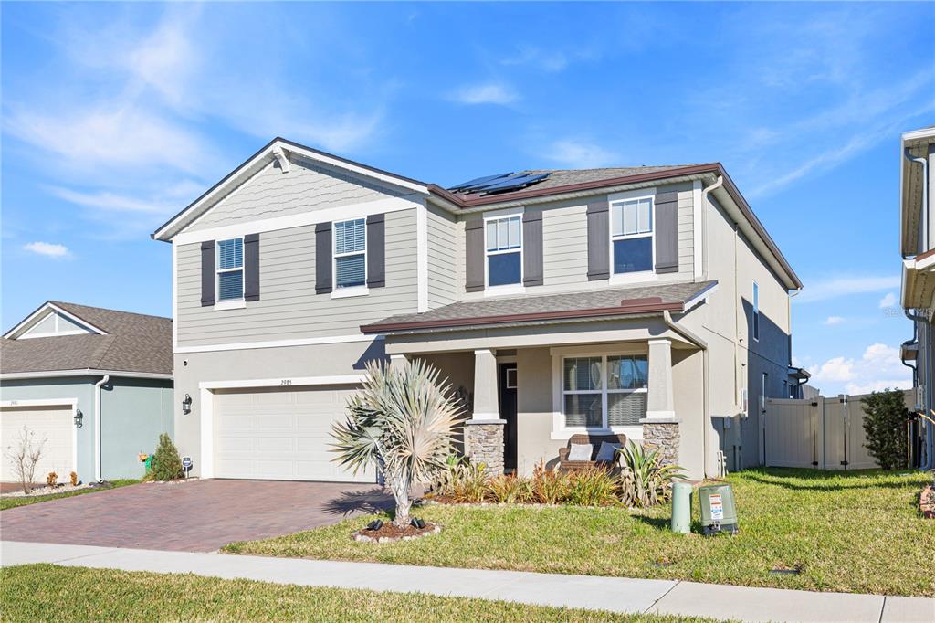 A two-story suburban house with light green siding, a two-car garage, and a front porch — 2985 AMBERSWEET PLACE, CLERMONT, FL