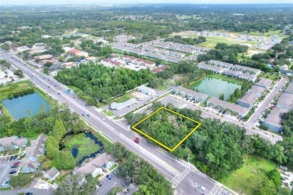 An aerial view shows a vacant, tree-covered lot outlined in yellow next to a busy road — 1240 BLOOMINGDALE AVENUE, VALRICO, FL