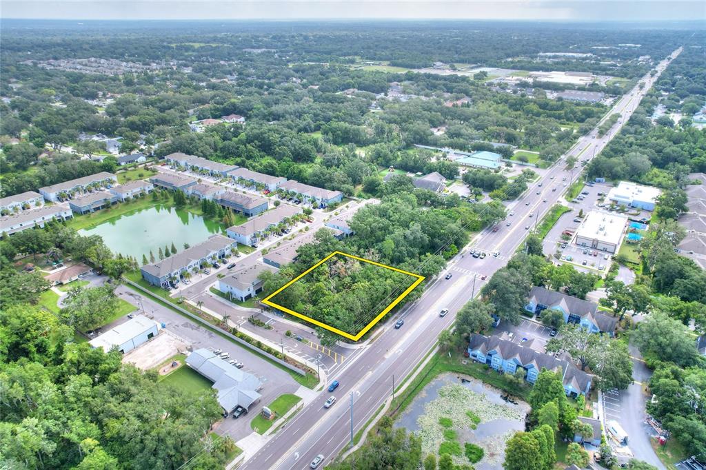An aerial view shows a vacant, rectangular wooded lot outlined in yellow next to a road — 1240 BLOOMINGDALE AVENUE, VALRICO, FL