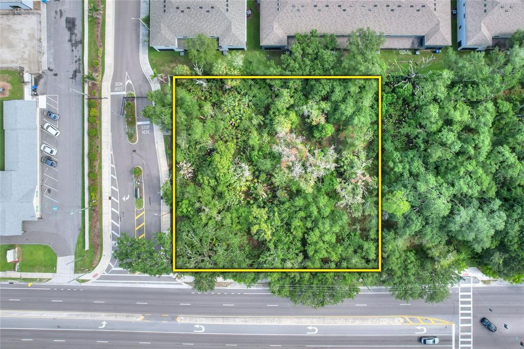 An aerial view shows a rectangular, tree-covered vacant lot outlined in yellow next to a road — 1240 BLOOMINGDALE AVENUE, VALRICO, FL