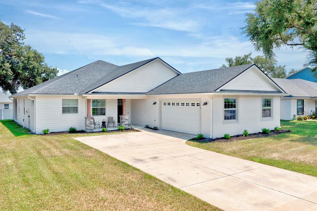 A single-story white house with a gray shingled roof and an attached two-car garage — 1415 MAGNOLIA LANE, AUBURNDALE, FL