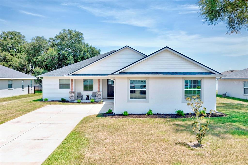 A single-story house with white siding, a concrete driveway, and a covered front porch — 1415 MAGNOLIA LANE, AUBURNDALE, FL