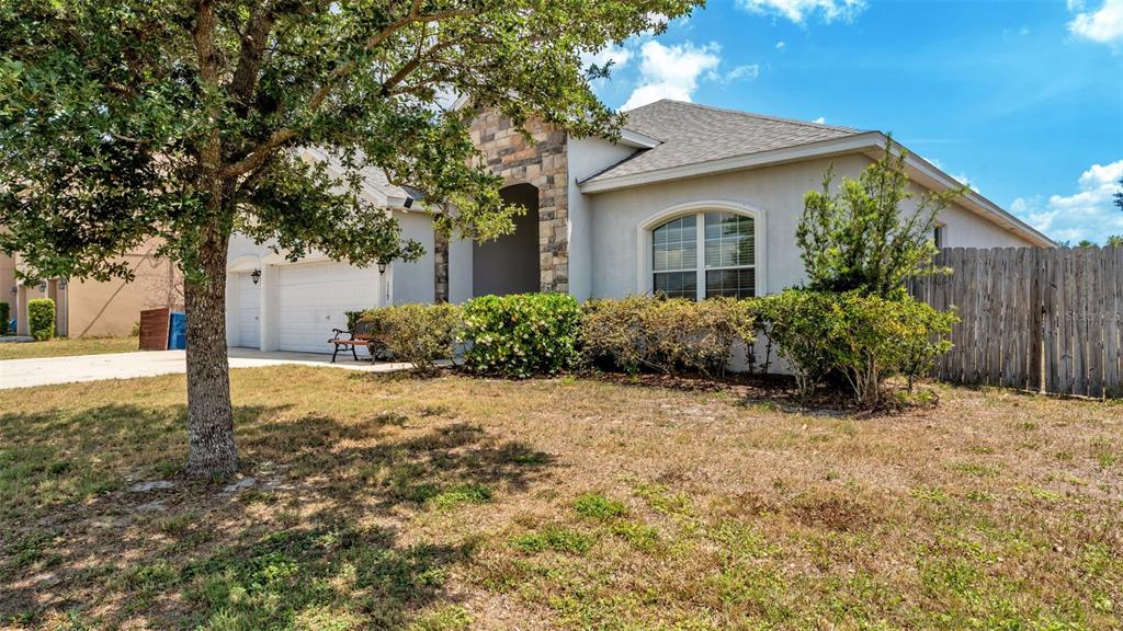 A single-story house with a stone facade, a two-car garage, and a wooden fence — 119 GERBER DAIRY ROAD, EAGLE LAKE, FL