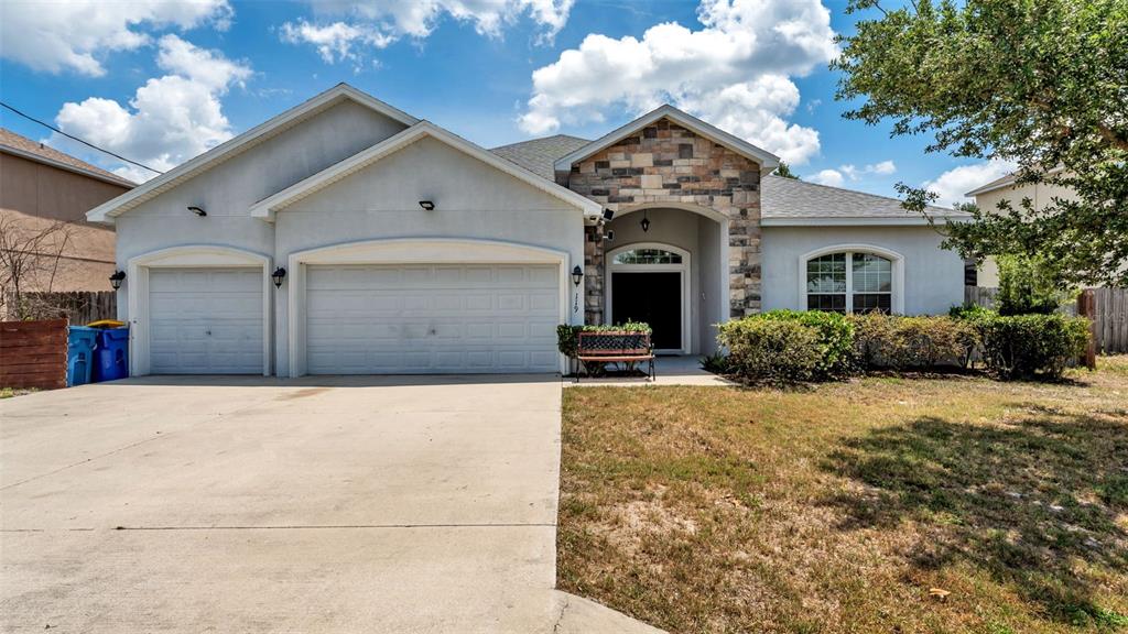 A single-story house with a three-car garage, stone facade accents, and a concrete driveway — 119 GERBER DAIRY ROAD, EAGLE LAKE, FL