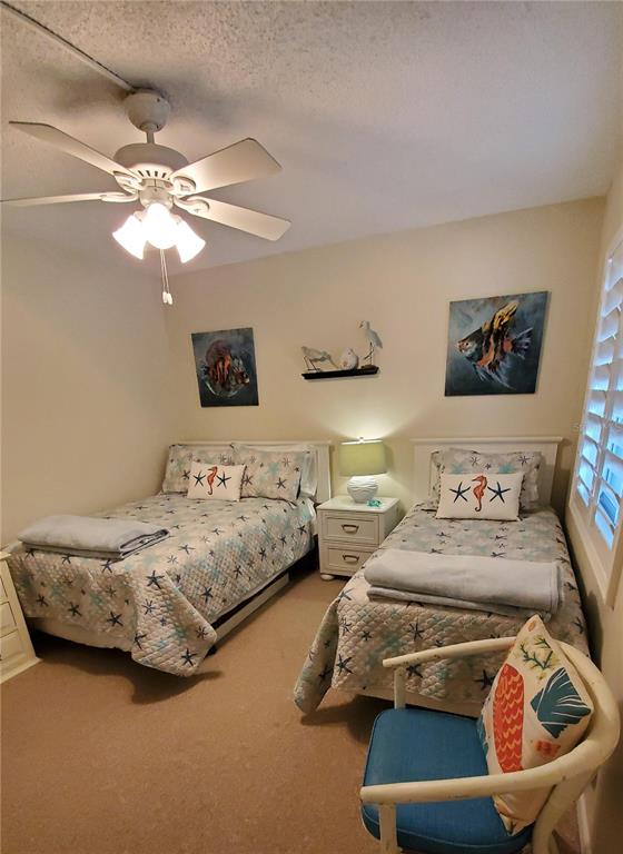 A bedroom features two twin beds, a ceiling fan, and coastal-themed wall art — 815 OCEAN SHORE BOULEVARD UNIT 10A, ORMOND BEACH, FL
