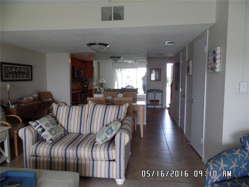 A living room with a striped sofa, tile flooring, and a view into the dining area — 815 OCEAN SHORE BOULEVARD UNIT 10A, ORMOND BEACH, FL