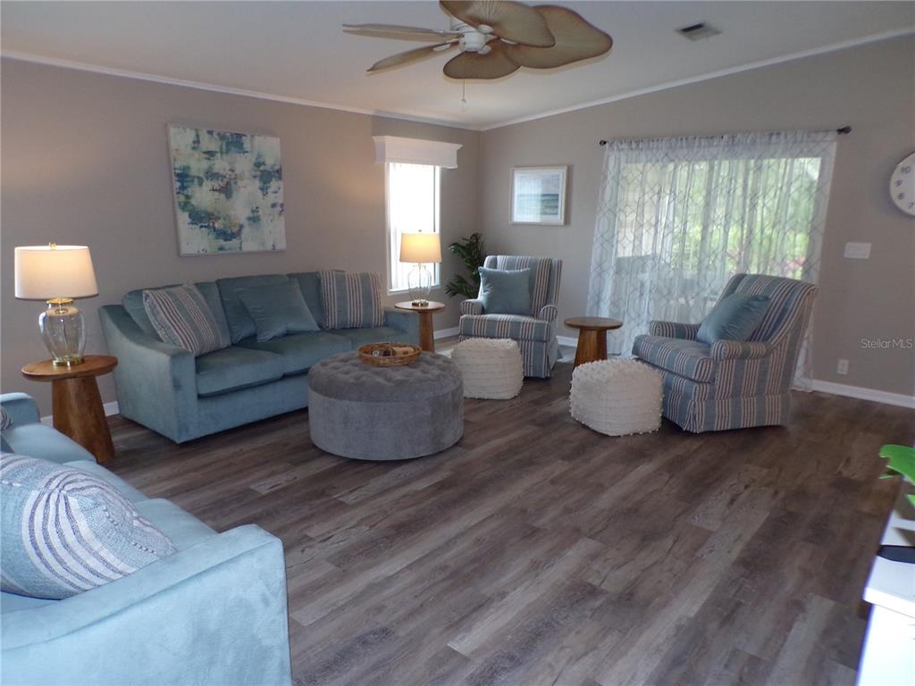 A living room features blue upholstered furniture, a gray ottoman, and wood-look flooring — 232 NATURES WAY, NORTH PORT, FL