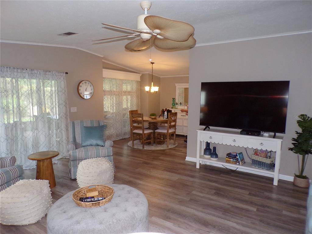 A living room and dining area feature wood-look flooring, a ceiling fan, and neutral walls — 232 NATURES WAY, NORTH PORT, FL