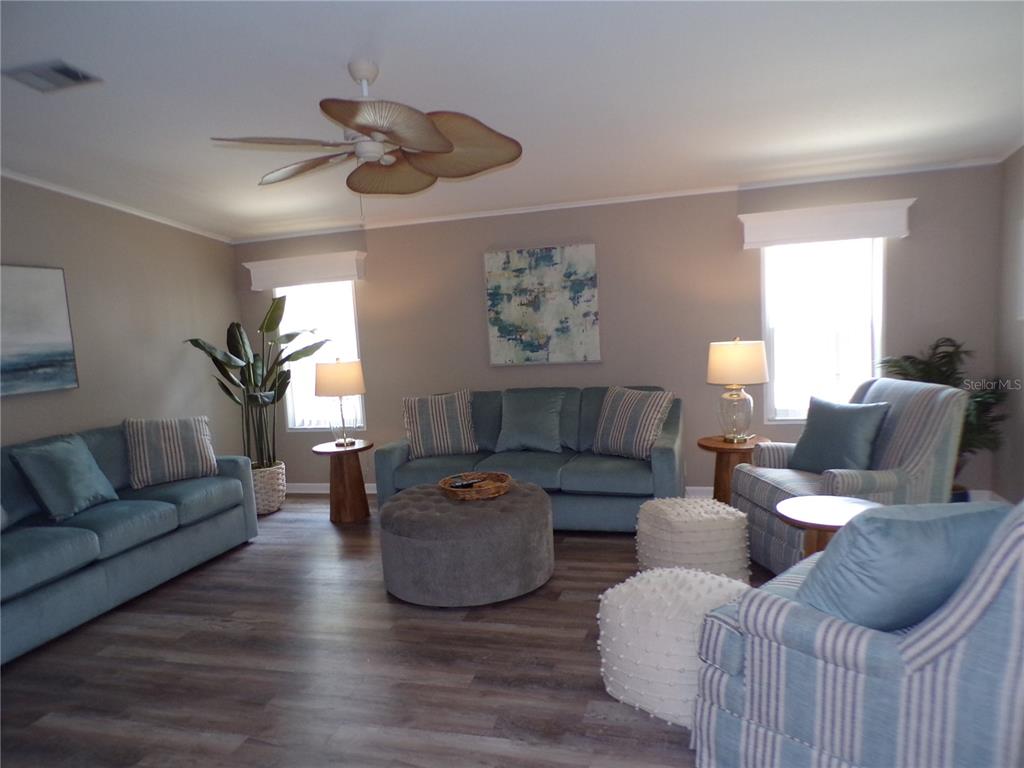 A living room features blue sofas, striped armchairs, a round ottoman, and wood-look flooring — 232 NATURES WAY, NORTH PORT, FL