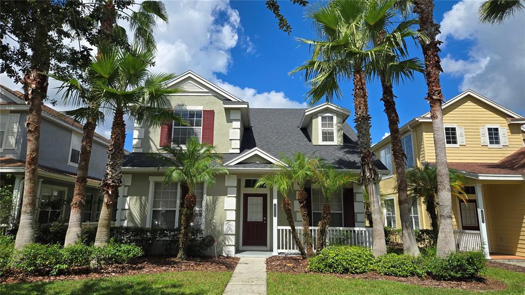 A two-story house with a green stucco exterior, red shutters, and palm trees in front — 20027 HERITAGE POINTE DRIVE, TAMPA, FL
