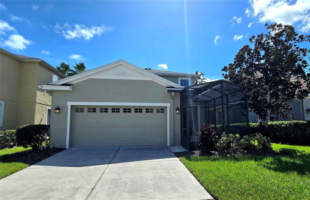 The exterior of a house features a two-car garage and a screened-in patio area — 20027 HERITAGE POINTE DRIVE, TAMPA, FL