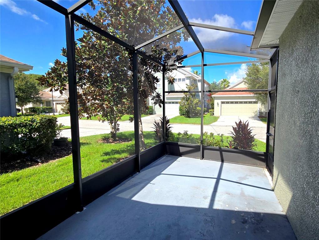 A screened-in patio with a concrete floor overlooks a suburban neighborhood with houses and trees — 20027 HERITAGE POINTE DRIVE, TAMPA, FL