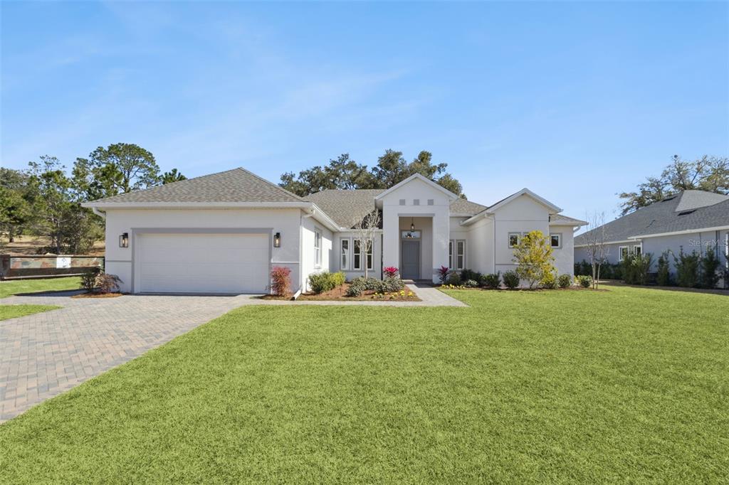 A single-story house with a white stucco exterior, a two-car garage, and a paved driveway — 4044 PINNACLE PLACE, LADY LAKE, FL